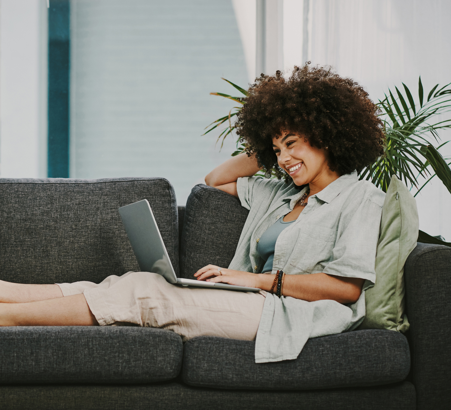 Full length shot of an attractive young woman sitting alone on her sofa at home and using her laptop Mommy Makeover in Phoenix, AZ