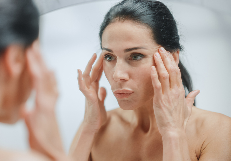 Caucasian Woman Looking in Mirror, Touching Beautiful Face, Soft Skin. Elderly Lady with Lush Black Hair. Female Beauty, Dignity, Grace. Sensual Wellness and Organic Skincare Products. Portrait Shot Facelift in Phoenix, AZ